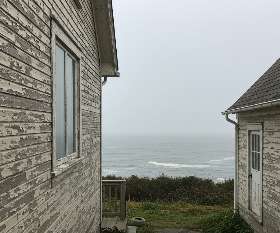 Coastal home with weathered exterior paint due to salty air and fog, highlighting the effects of coastal climate on paint longevity